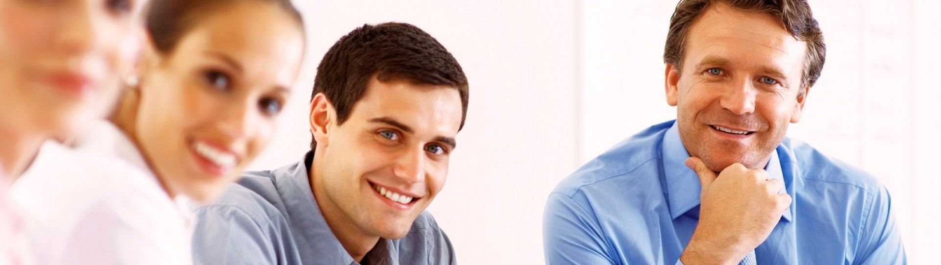 Vier Personen sind in einem Meeting, lächeln und diskutieren.