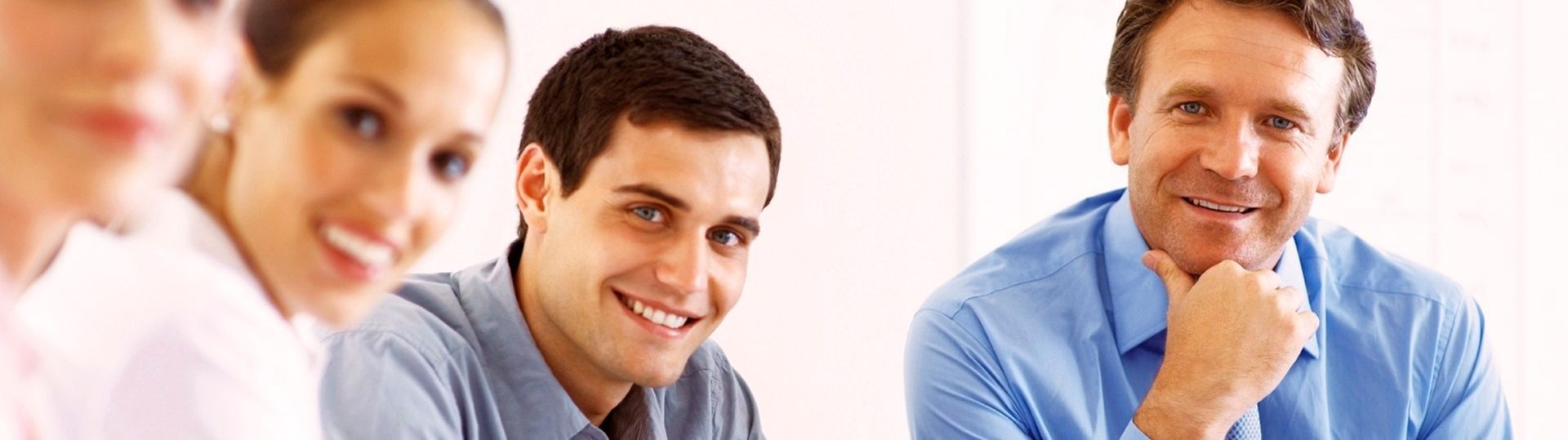 Vier Personen sind in einem Meeting, lächeln und diskutieren.