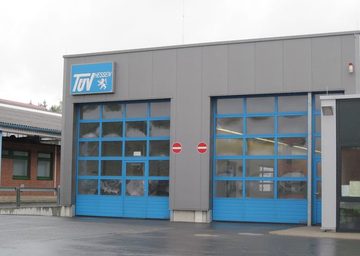 Ein Gebäude mit einem blauen Schild mit der Aufschrift "TUEV HESSEN" und blauen Türen.